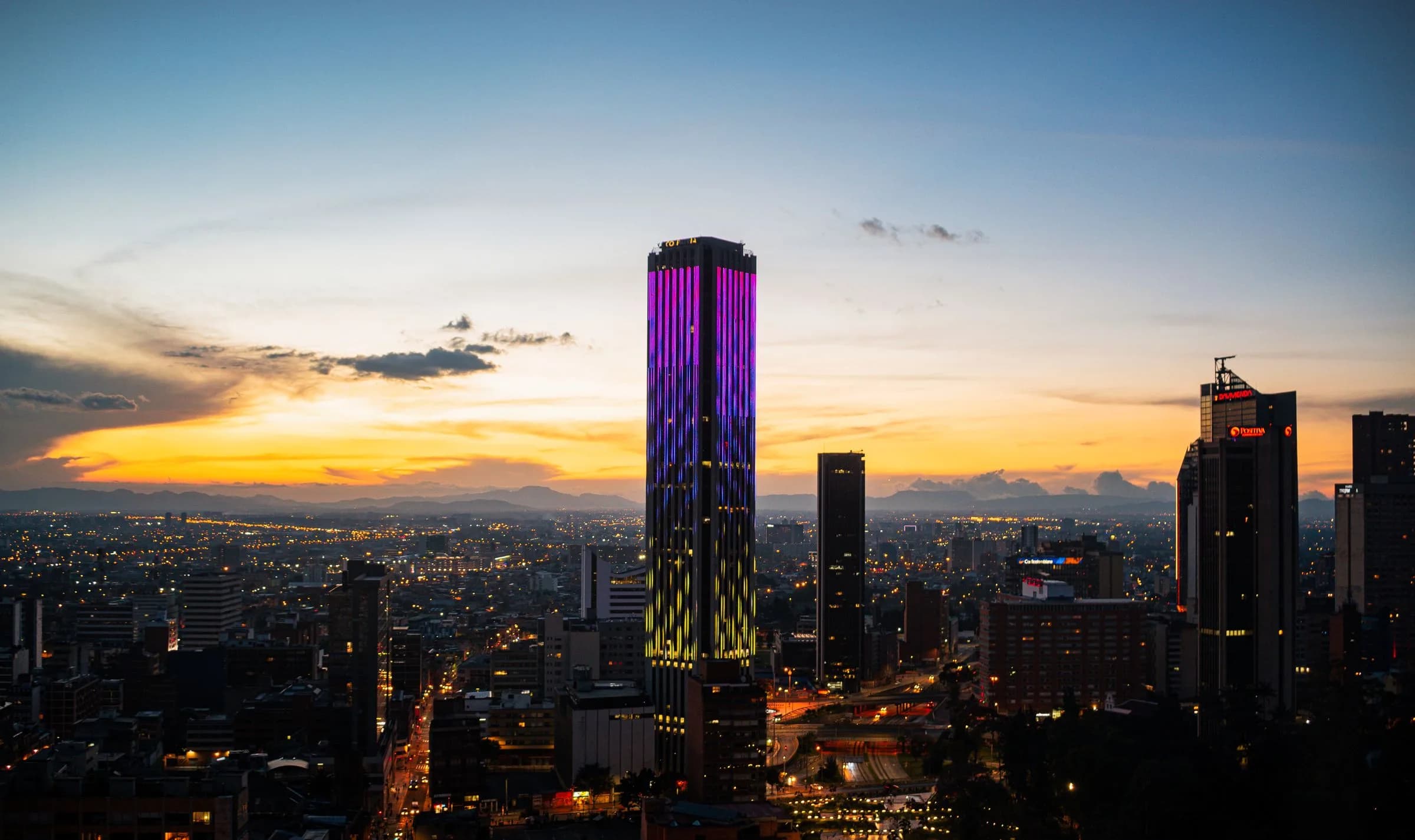 Skyline moderno de Bogotá al atardecer con la Torre Colpatria iluminada